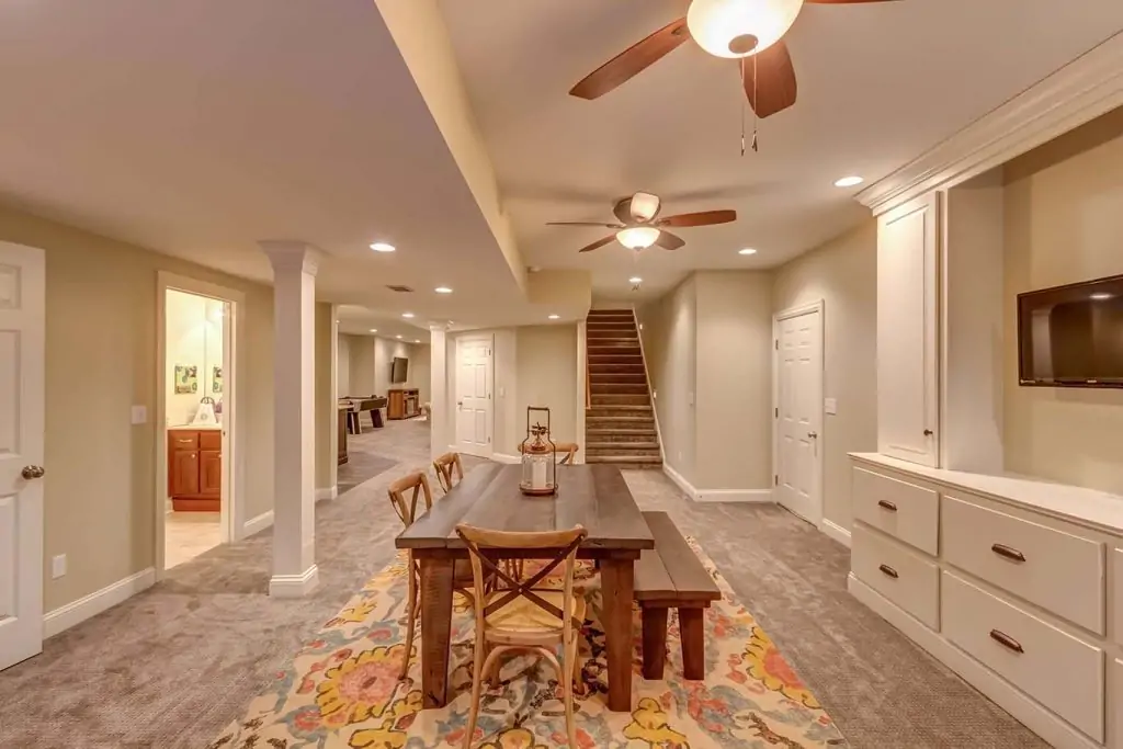 Farmhouse style wooden table, chairs, and bench on carpet floors of finished basement home addition.
