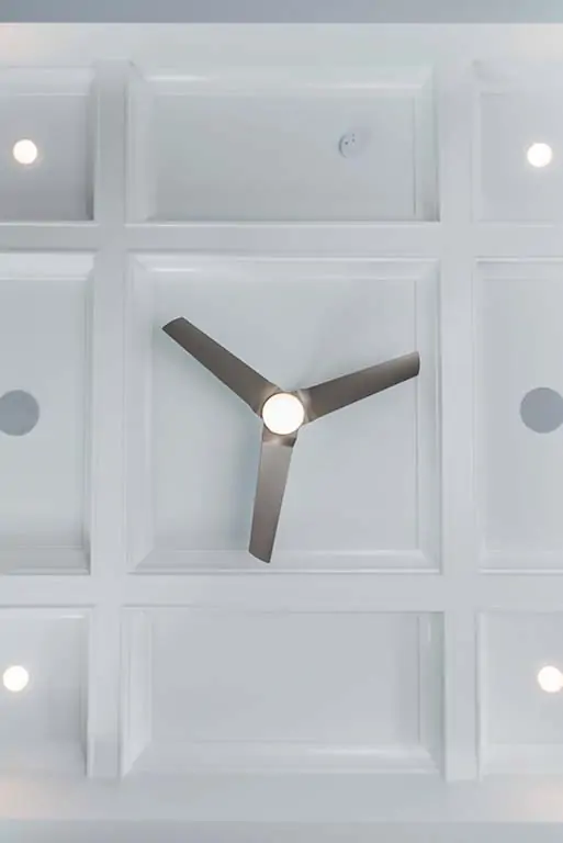 Detailed view looking up at a ceiling fan with a light in a white tray ceiling.