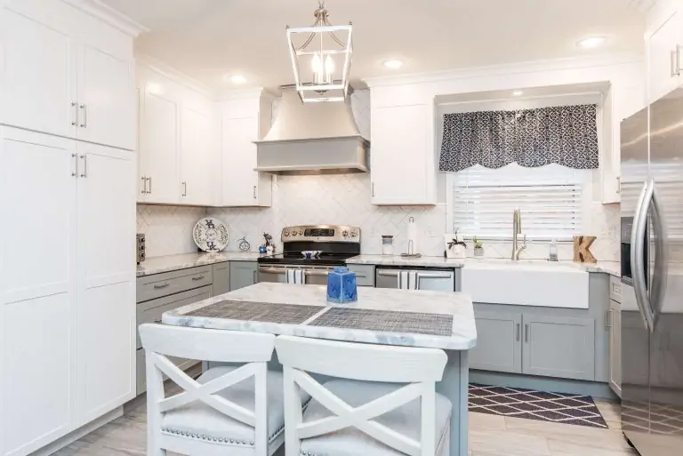 Bright white residential kitchen remodeling with light gray cabinets, stainless steel appliances, and a white farmhouse sink.