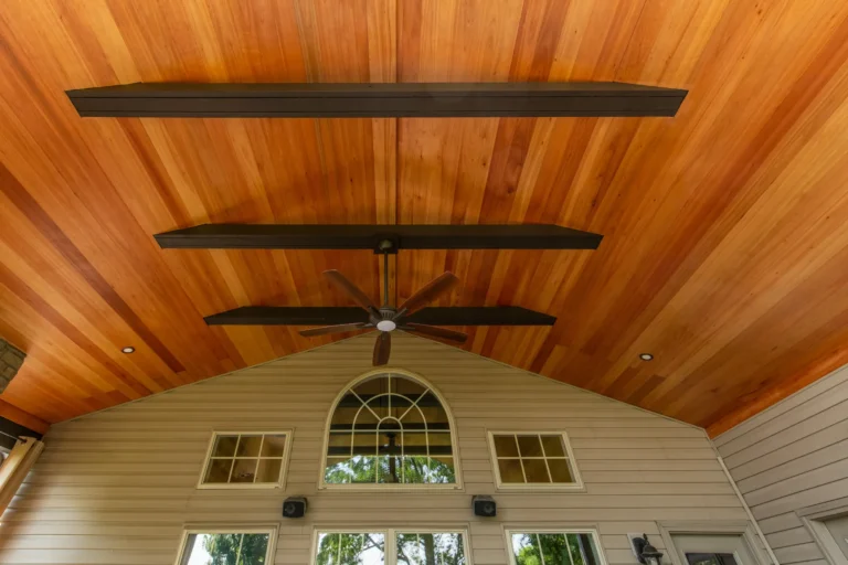 Upward view of a vaulted cedar ceiling with dark wood beams and a ceiling fan on a covered porch in Lexington, KY.